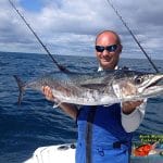 Captain Keith Logan holding a king mackerel on the the boat in the ocean on fishing charter in myrtle beach